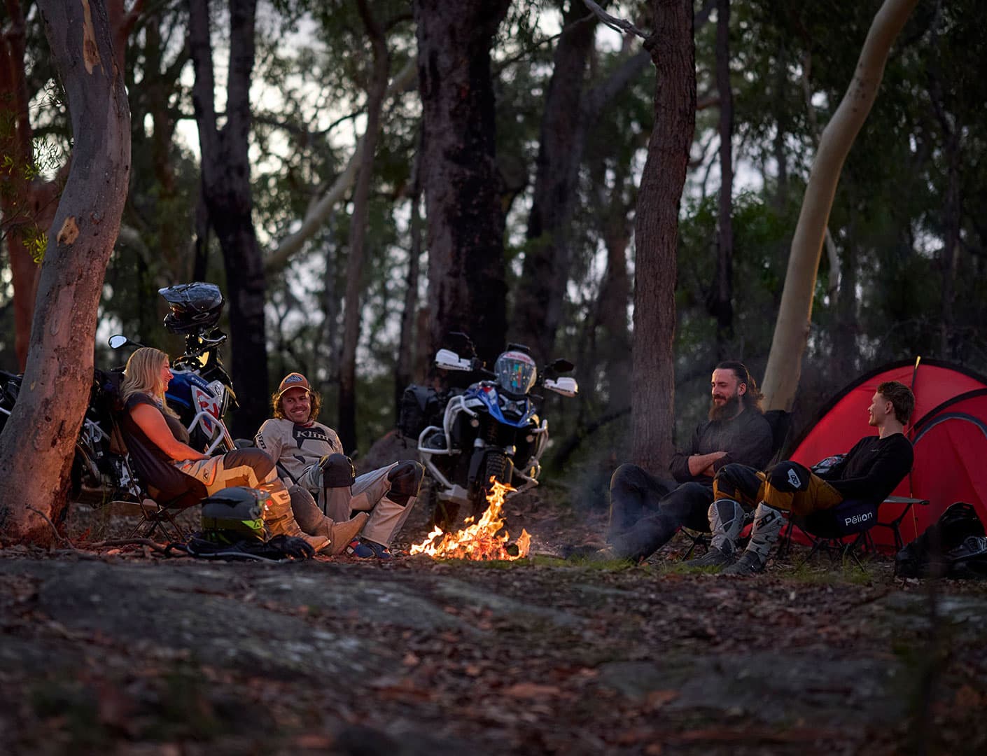 Motorcycle riders relaxing around a campfire in the forest